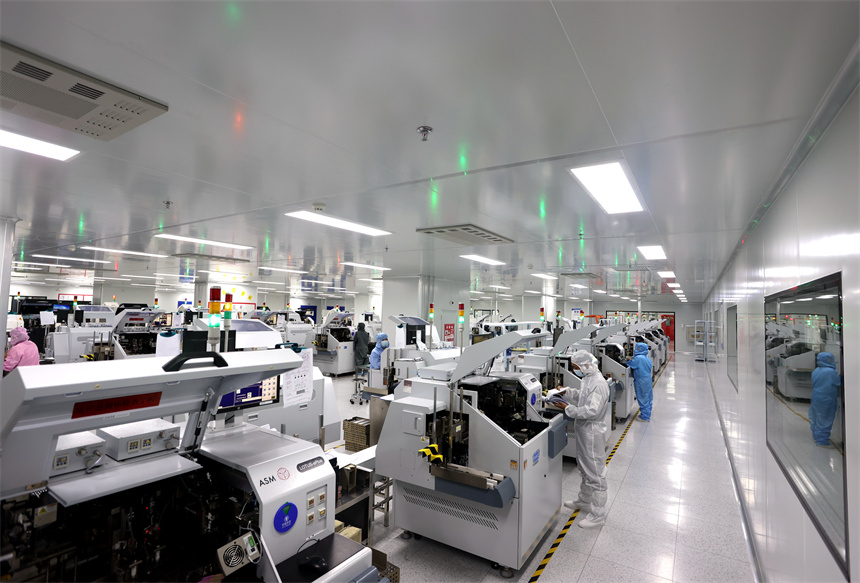 Workers in cleanroom suits operating a chip packaging line